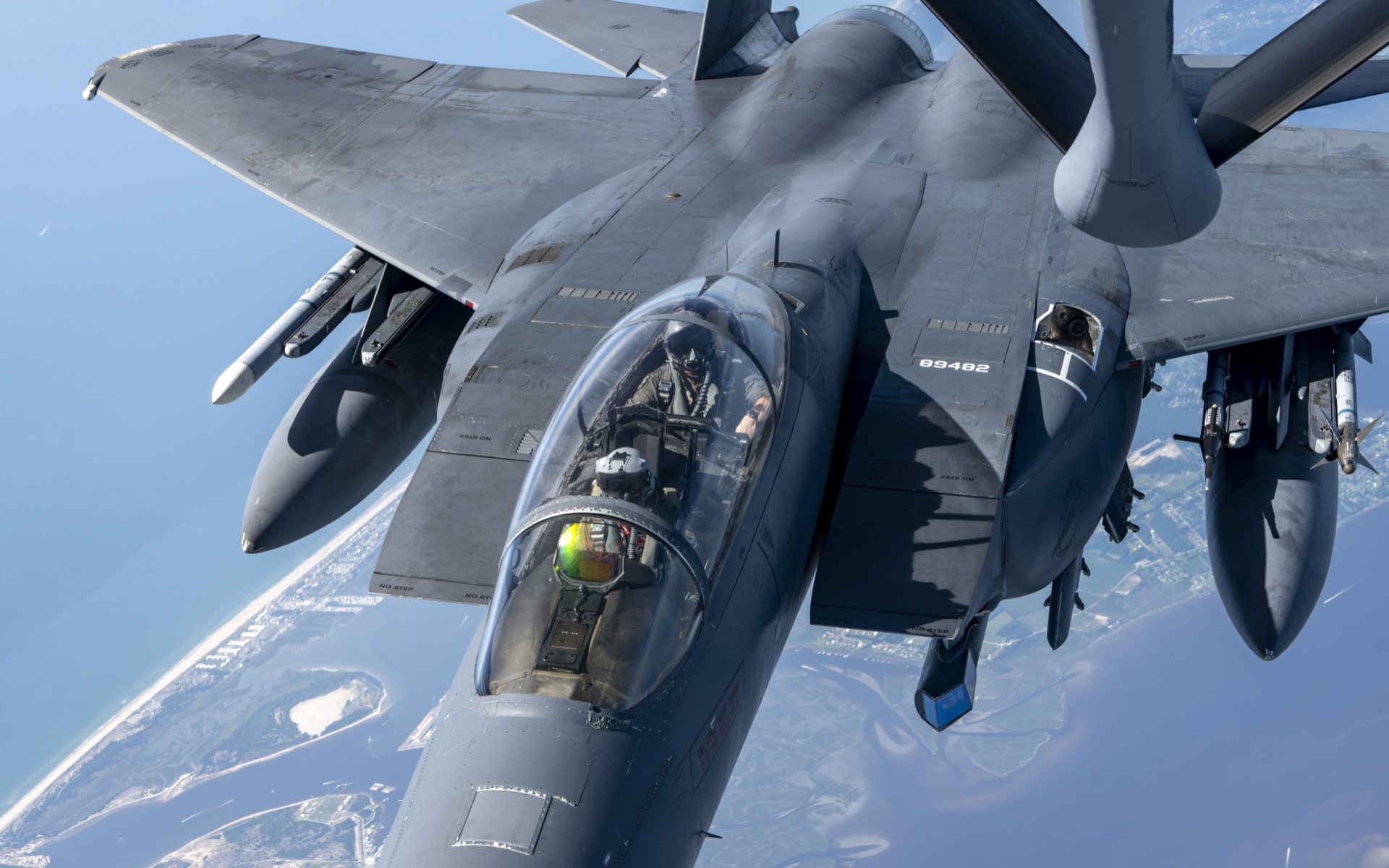 F-15 fighter jet receiving aerial refueling over coastal terrain