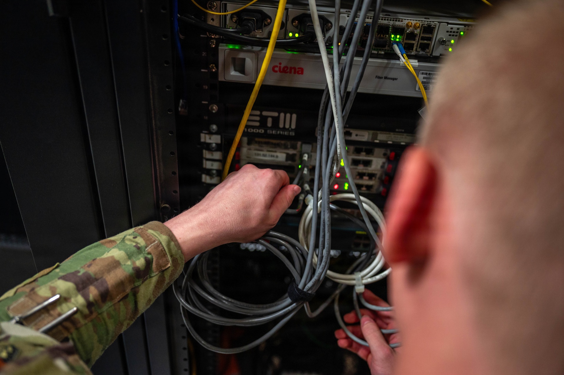 Military technician installing network cables in secure communications server rack