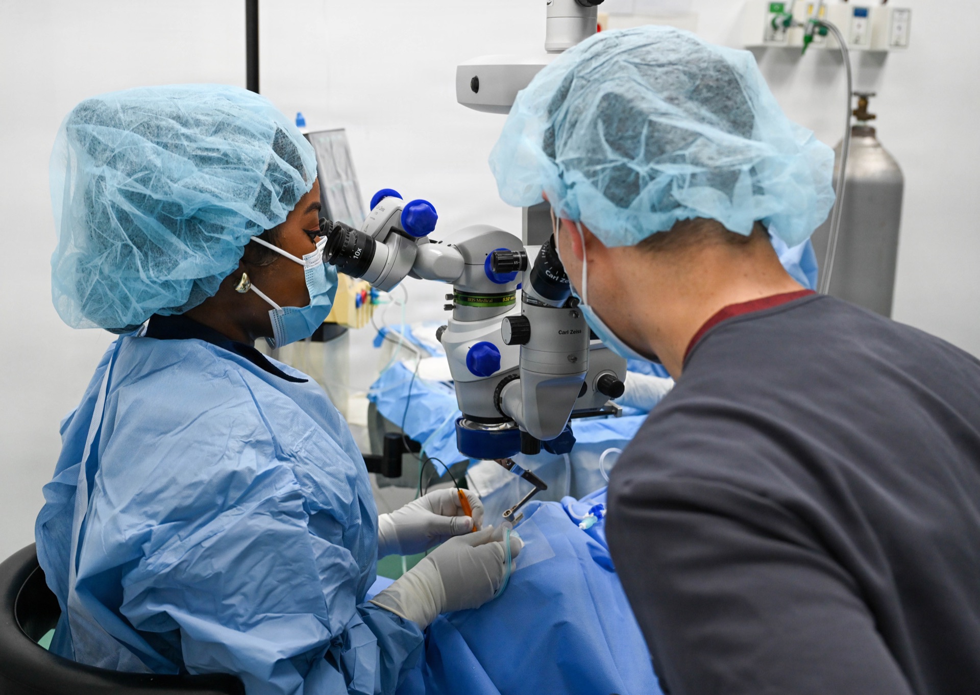 Surgeons performing precision eye surgery using operating microscope in clinical setting