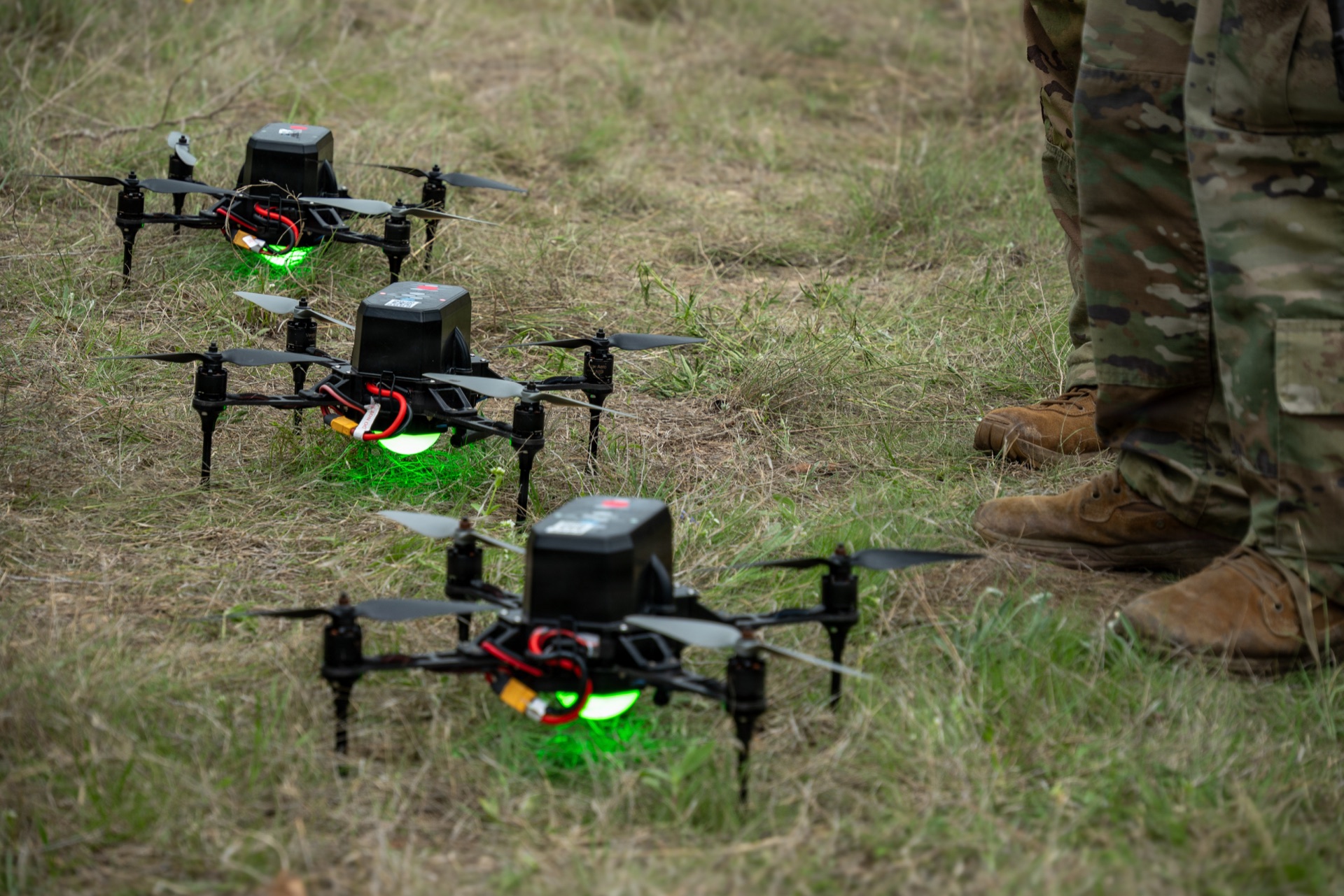 Military autonomous drone systems lined up on grass field during field demonstration